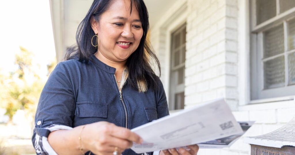Woman holding direct mail marketing piece encouraging customer engagement