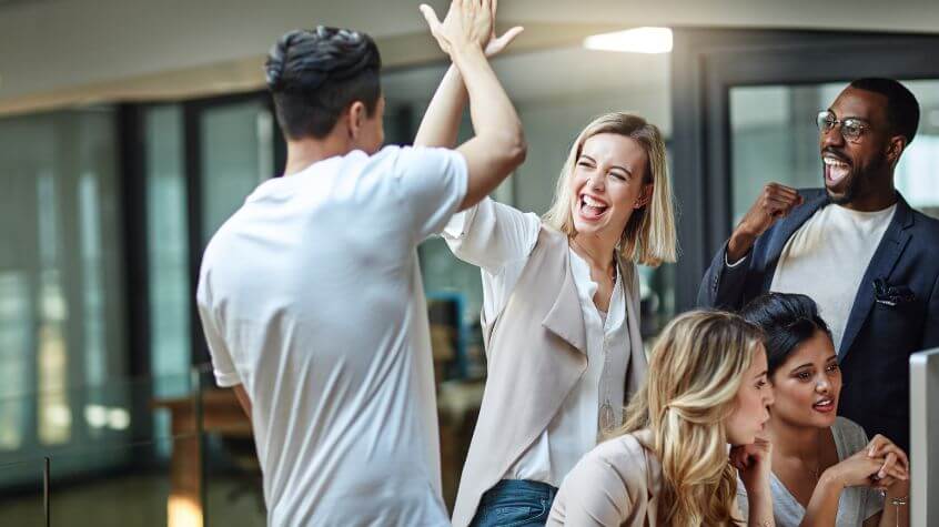 Coworkers celebrating success after Integrating Market Research and Competitive Analysis